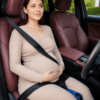 Pregnant woman using a pregnancy seat belt adjuster strap with clip to help position the lap belt below the baby bump while seated in a vehicle.